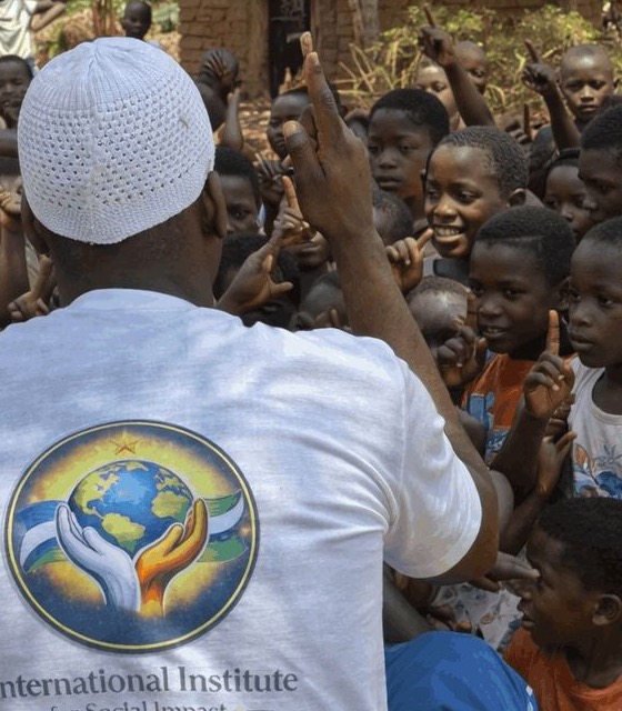A member of the Institute team wearing a white shirt with the Institute logo, talking with villagers